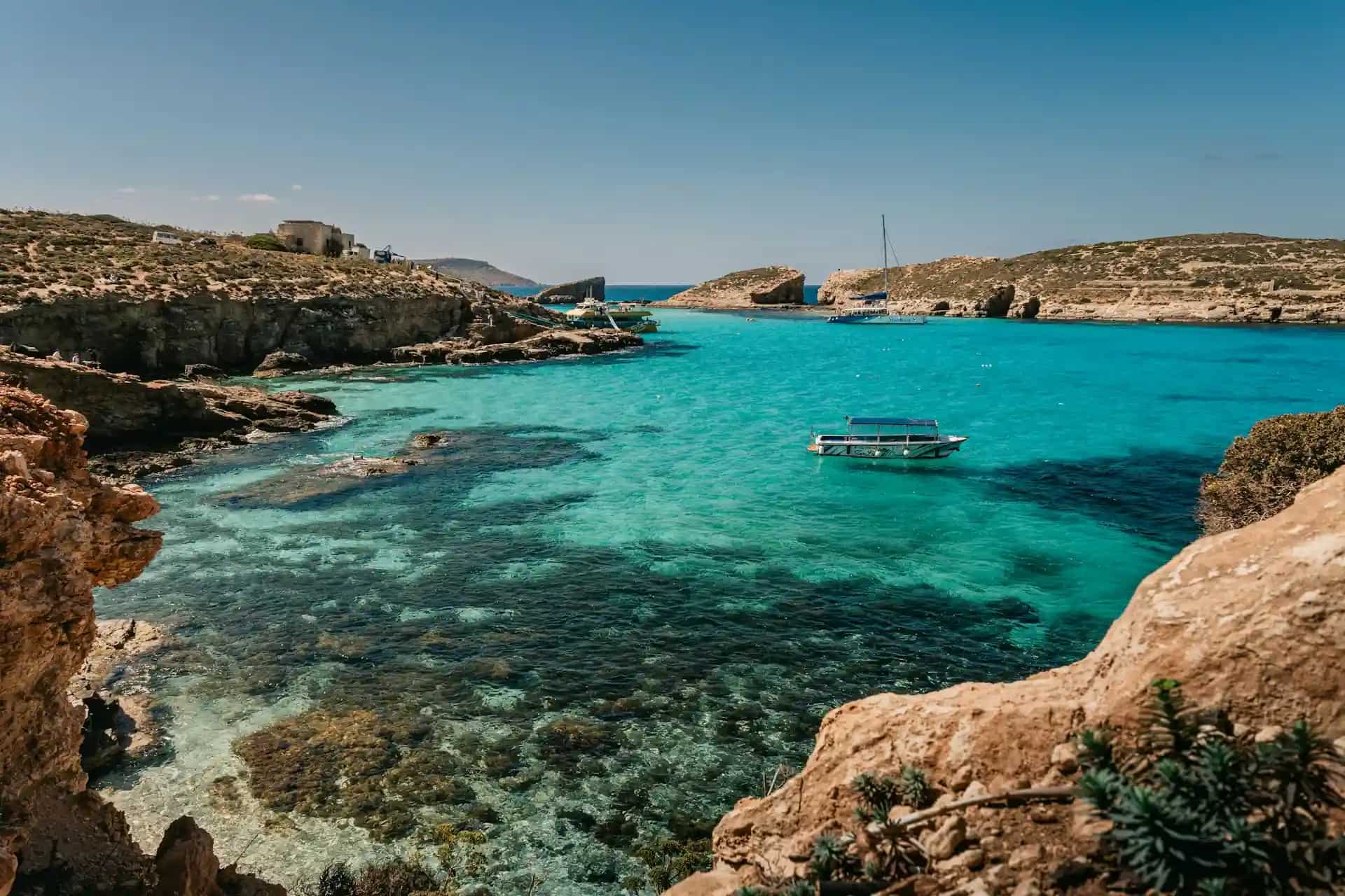 Blue Lagoon Comino Malta — turquoise water between rocky limestone cliffs with a boat at anchor