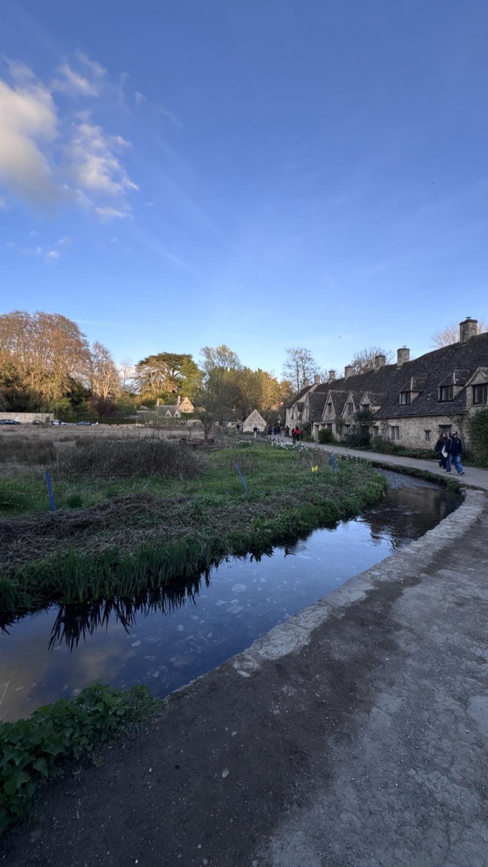 Arlington Row honey-stone cottages reflected in the River Coln water meadow at Bibury, Cotswolds