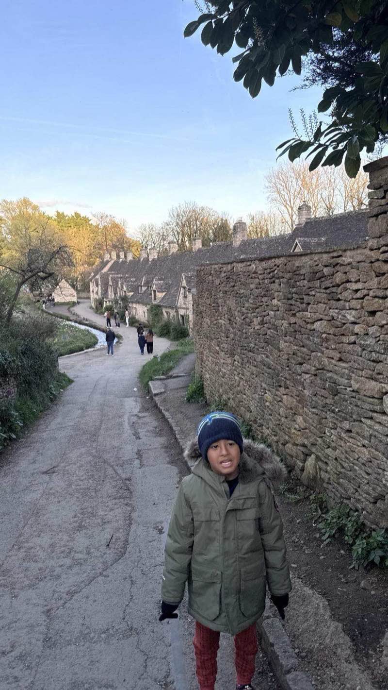 The lane alongside Arlington Row cottages in Bibury with dry stone wall and honey-stone buildings