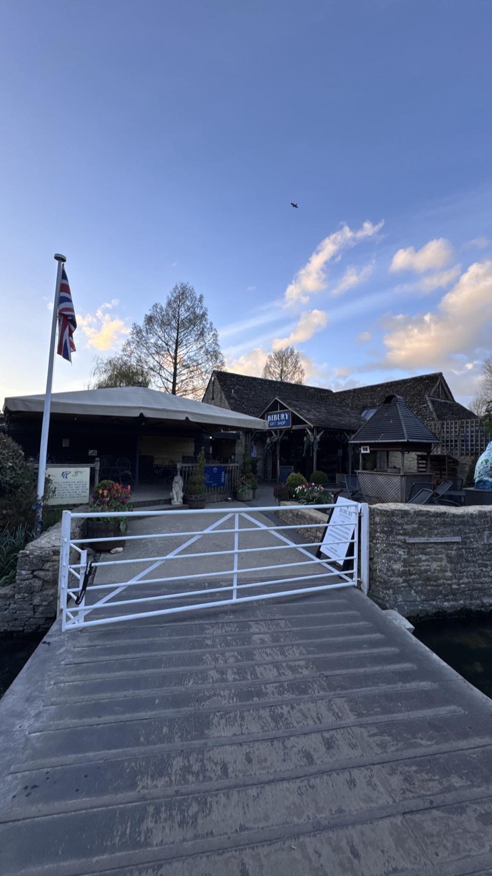 The Swan Hotel at Bibury with Union Jack flying, viewed from the bridge over the River Coln