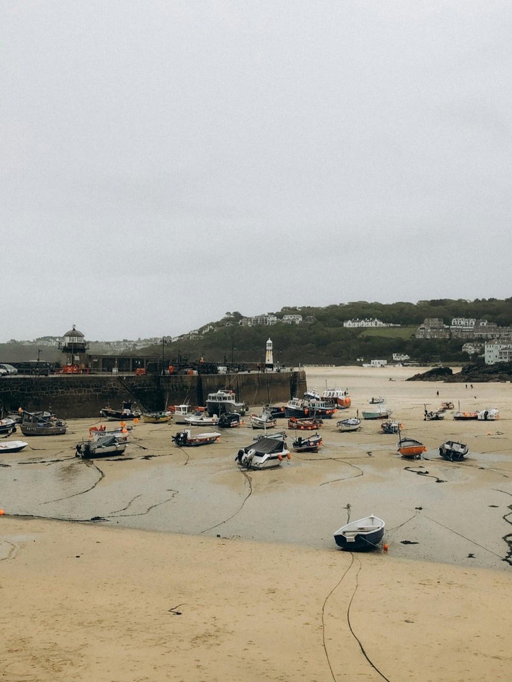 St Ives harbour at low tide, Cornwall — fishing boats moored on sand with the town and lighthouse in the background