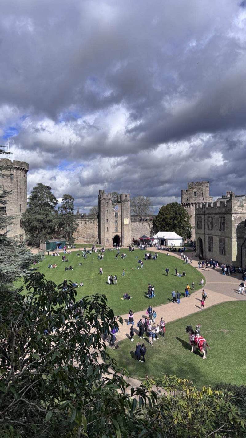 Warwick Castle inner courtyard seen from the ramparts, with visitors exploring below