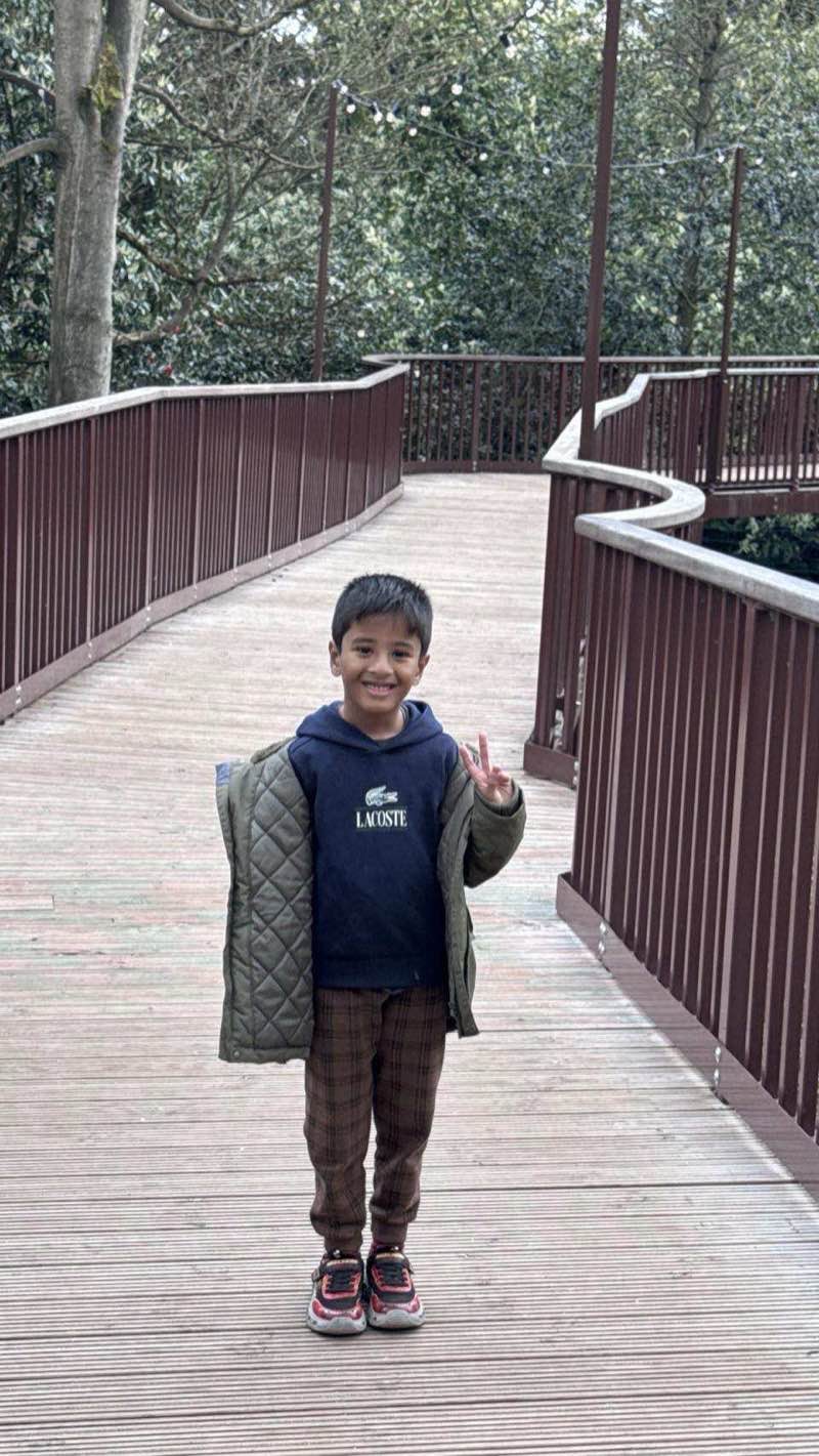 Child walking along the elevated treetop walkway winding through the woodland at Warwick Castle